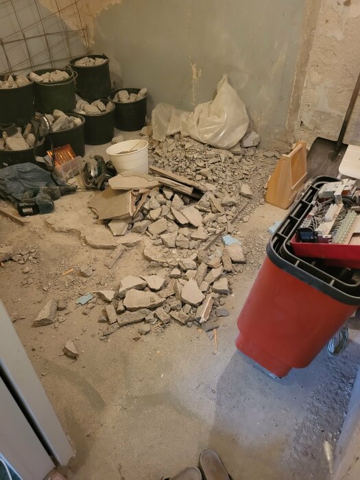 Renoveringsarbete i källare med borttaget golv och samlade betongrester.