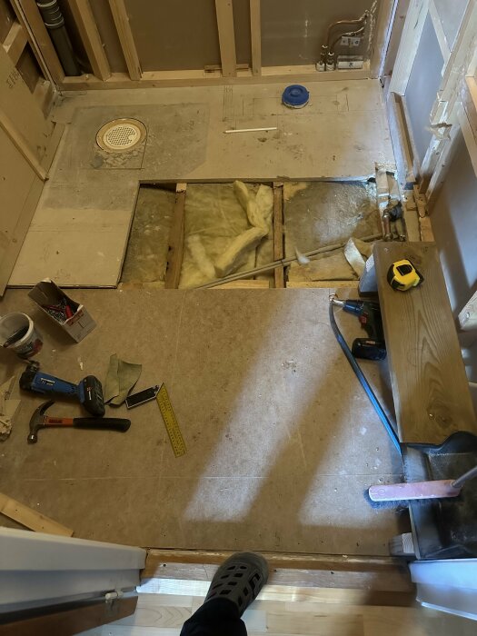 Renoveringsarbete i badrum med verktyg och blottat bjälklag redo för golvvärmeinstallation.