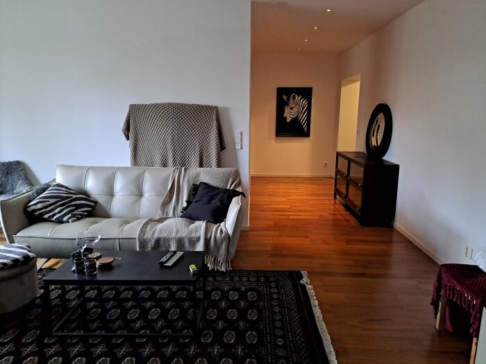 Vardagsrum med soffa, dekorativ matta, sideboard och zebra-tavla, optimerat för ljudupplevelse.
