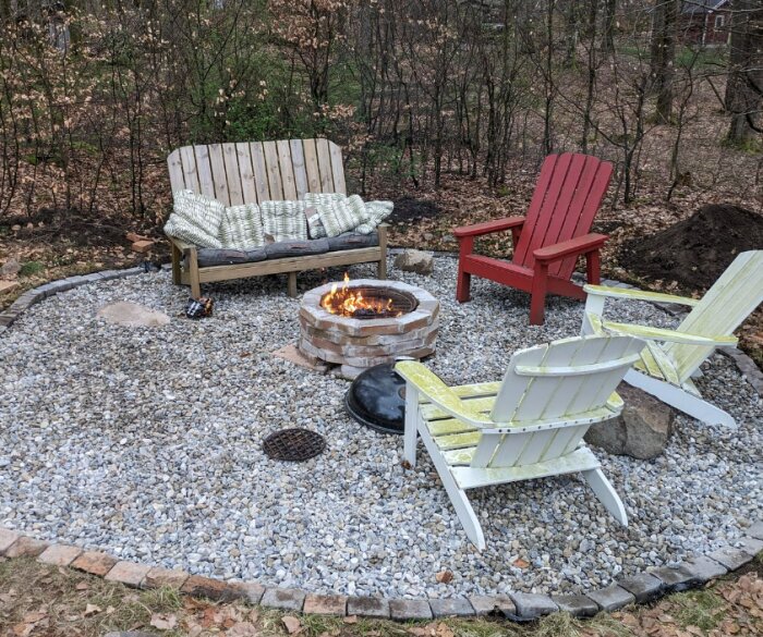 Eldplats med svart vit sjösten, träsoffa och röd stol, och Cool-Well installation i trädgård.