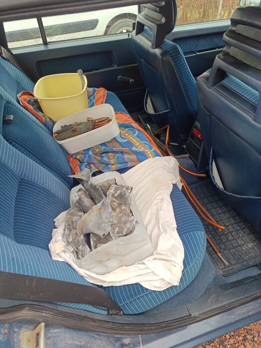 Metallskrot i bakluckan på en bil inklusive en hink och en låda med kopparkabel och blybitar.