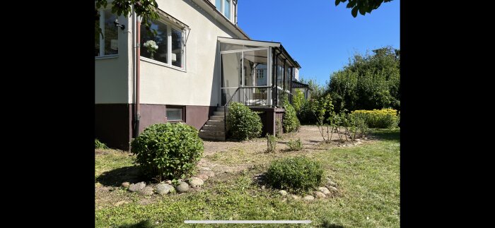 Uteplats med en gammal markstensgång och ojämna ytor, föreslagen för renovering och altanbygge intill ett hus.