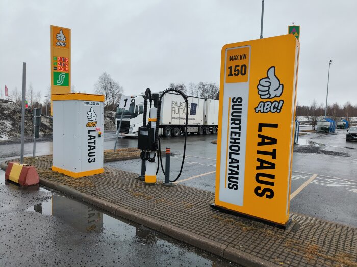 Elbilsladdningsstation med skyltar för 150 kW maxladdning vid ett vått parkeringsområde.