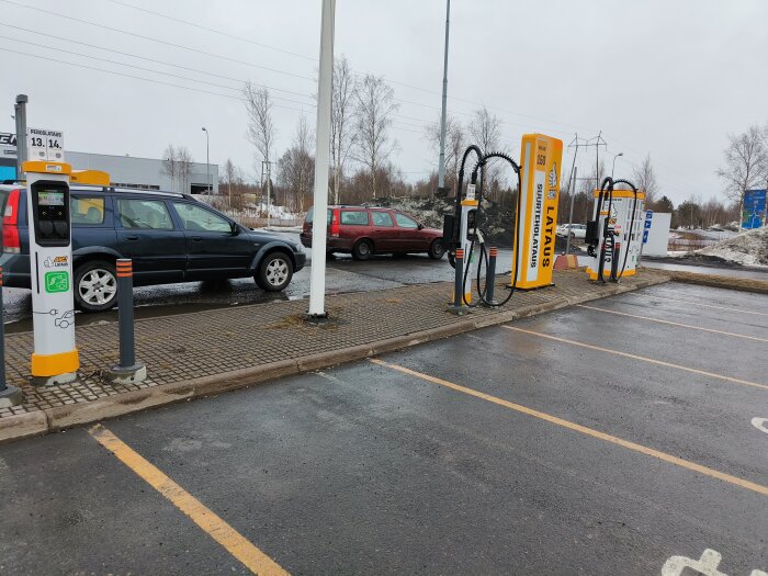 Elektriska fordonsladdare på en parkering med markerade laddplatser och en bil parkerad.