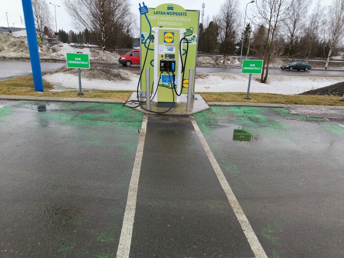 Elektrisk laddstation för fordon med "endast för elbilar"-skyltar och våt parkeringsplats, utan anslutna fordon.