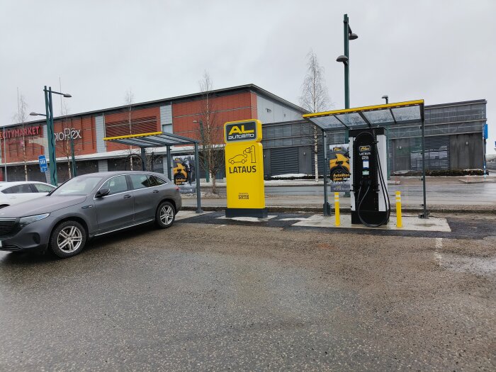 Elbilsladdningsstation med en bil parkerad framför i en stadsmiljö, under dagtid.