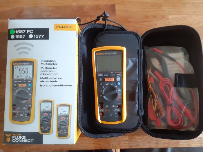 Fluke isolationsmultimeter med förvaringsväska och tillbehör framför förpackningen.