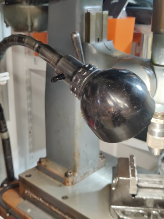 Arbetsbelysning monterad på en verktygsmaskin i verkstaden, med fokus på lampan och fixeringen.