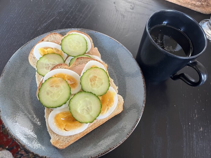 Rostmackor med ägg och skivad gurka på en tallrik bredvid en kopp te.