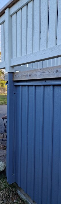 Stabil räckeskonstruktion vid en blå yttervägg och vit staketdel, ej markförankrad.