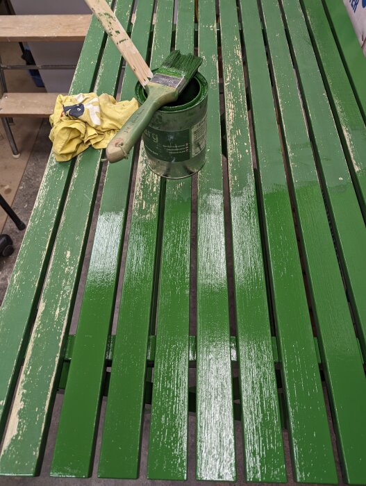 Ett nymålat grönt träbord med pensel och öppen färgburk ovanpå.