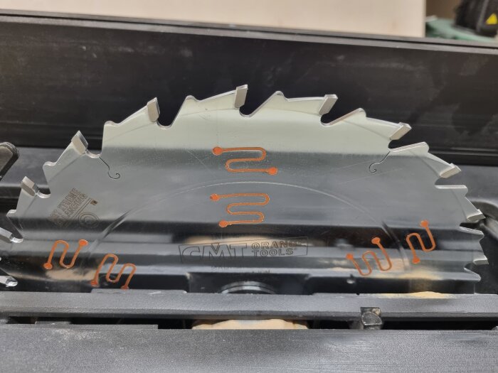 Närbild av en CMT klyvklinga för träbearbetning med sylvassa tänder och orange detaljer.