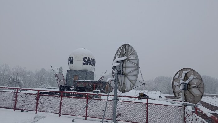 SMHI:s paraboler täckta av snö på ett tak med text "SMHI" synligt trots snöfallet.