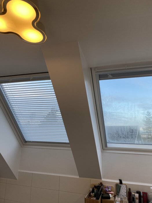 Nymålat tak och fönsterkarm i ett rum med utsikt, inkluderar en modern lampa och badrumsartiklar.