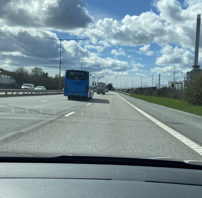 Vy från bil på en 80-väg med tomt höger körfält, mittkörfält med trafik och en blå buss framför.