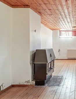 Källarplan med gammal kamin kopplad till skorsten, trägolv och paneltak, plats för garderob nämns.