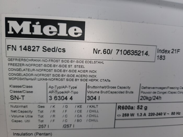 Miele frysskåps etikett visar modellnummer FN 14827 och specifikationer som serienummer och kylkapacitet.
