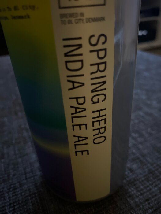 Närbild på en ölburk med texten "SPRING HERO INDIA PALE ALE" mot en oskarp bakgrund.
