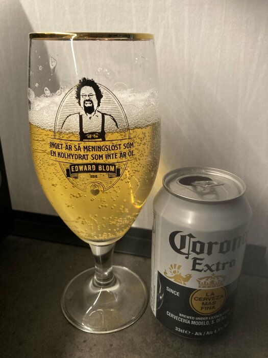 Ölglas med skum och citat av Edward Blom bredvid en burk Corona Extra.