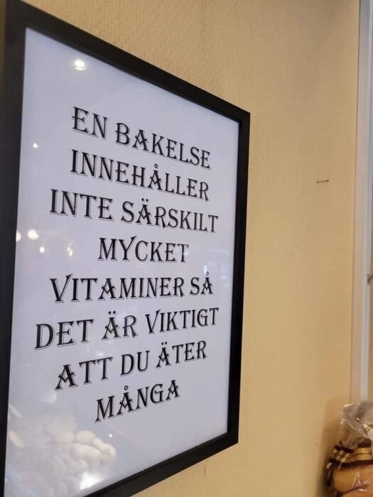 Inramad text på vägg med budskapet "En bakelse innehåller inte särskilt mycket vitaminer så det är viktigt att du äter många".