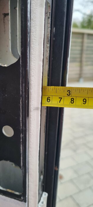 Måttband visar avståndet vid en dörrkarm där låshuset är monterat.