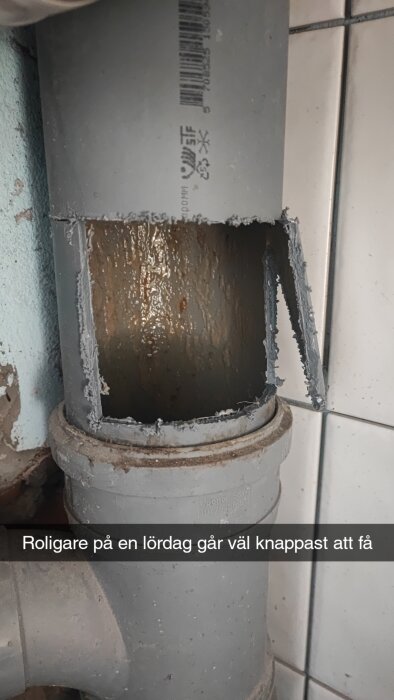 Avsågat plaströr med klart synlig rektangulär öppning och råa kanter mot kakelvägg.