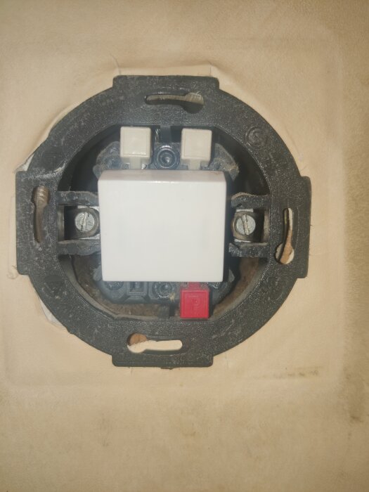 En strömbrytare med en röd markering och ett 'P' på en knapp, monterad på en vägg.