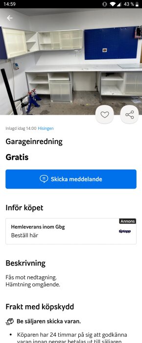 Vit arbetsbänk och väggskåp i ett garage med blå verktygstavla och golvstående skruvstäd.