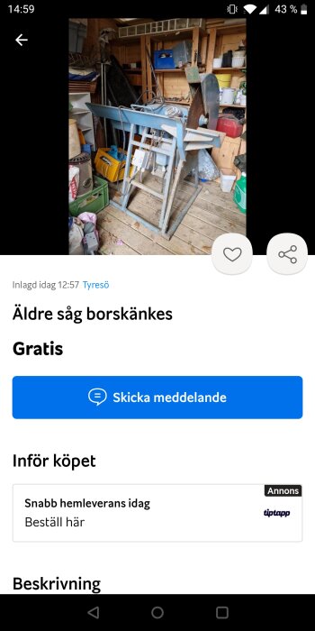 Oorganiserad verkstad med en äldre blå bandsåg, diverse verktyg och oordnade föremål.