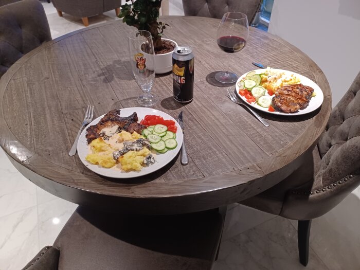 Två tallrikar med middag på ett runt matbord, dryck och bestick, i ett modernt kök.