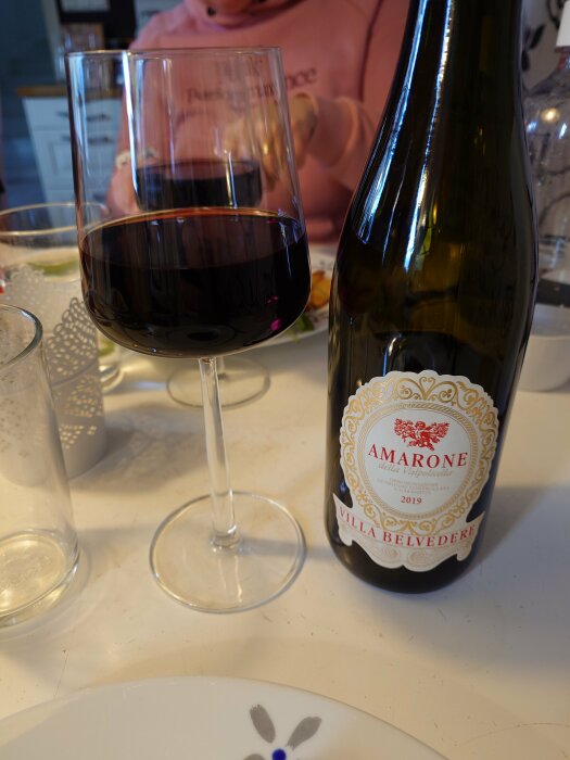 Flaska och glas fyllt med rödvin, etikett visar Amarone della Valpolicella 2019.