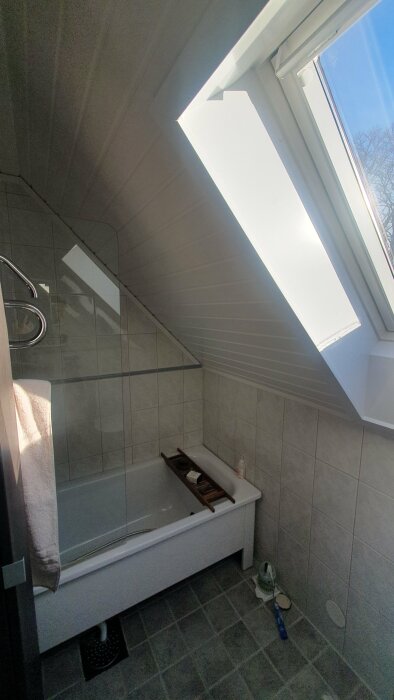 Badrum med snedtak, badkar och fönster i tak, fråga om placering för badrumsfläkt.