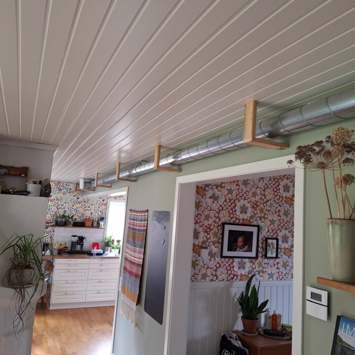 Interiör med synligt ventilationsrör längs taket i ett hem med öppen planlösning.