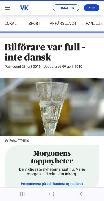 Champagneglas delvis fyllt med bubblig dryck i oskarp bakgrund.