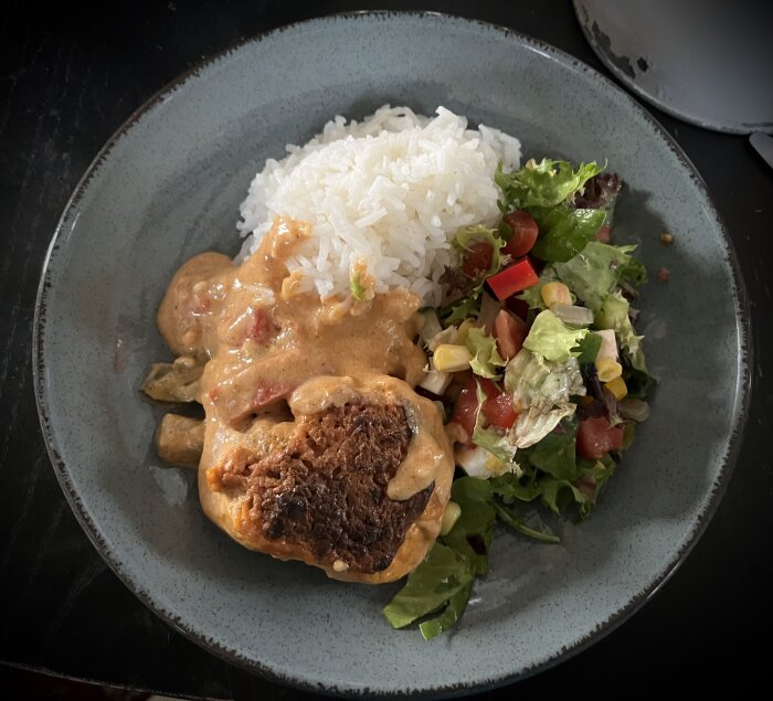 Kycklinglårfilé med Tex Mex-sås, vit ris och färgrik sallad på en keramiktallrik.