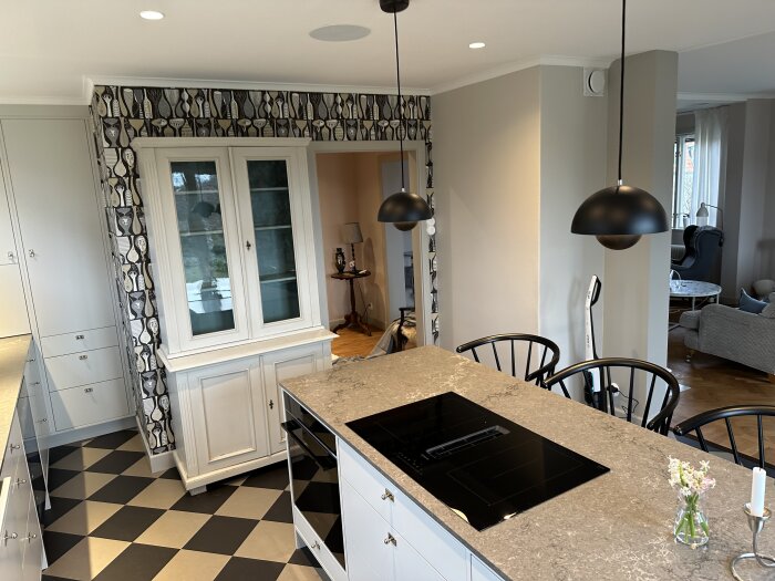 Nyrenoverat kök med mönstrad tapet, schackrutigt golv, vita skåp och öppen planlösning mot vardagsrum.