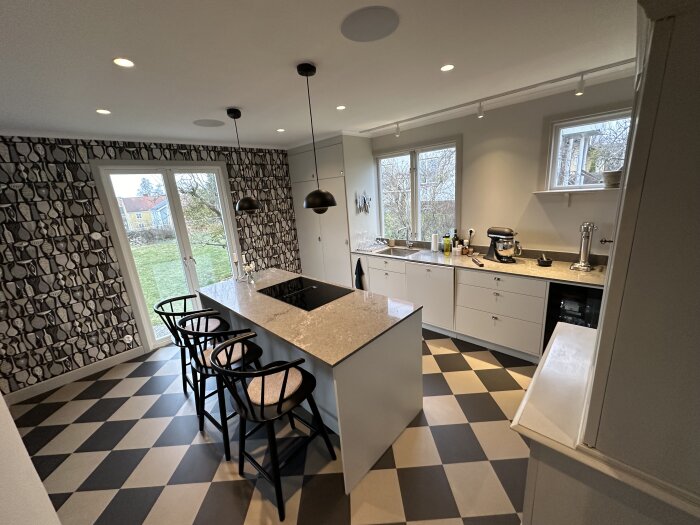Nyrenoverat kök med schackrutigt golv, mönstrade tapeter och modern inredning.