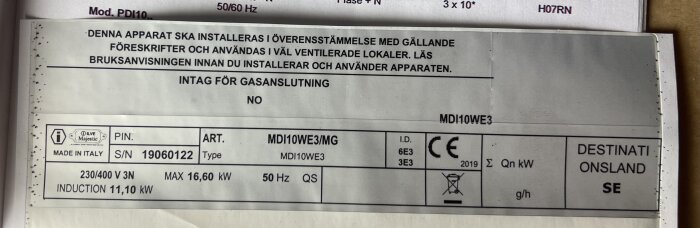 Klisteretikett på spis visar modell, tillverkningsland, serienummer, spänning, kapacitet och CE-märkning.