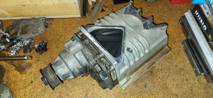 Kompressordel från Eaton TVS R1320 bearbetad för Porsche 944, omgiven av verktyg och skruvar.