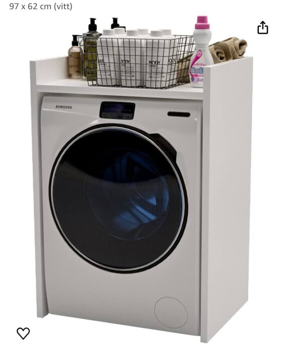 Vit bänkskiva ovanpå en tvättmaskin med en korg, flaskor och handdukar på.