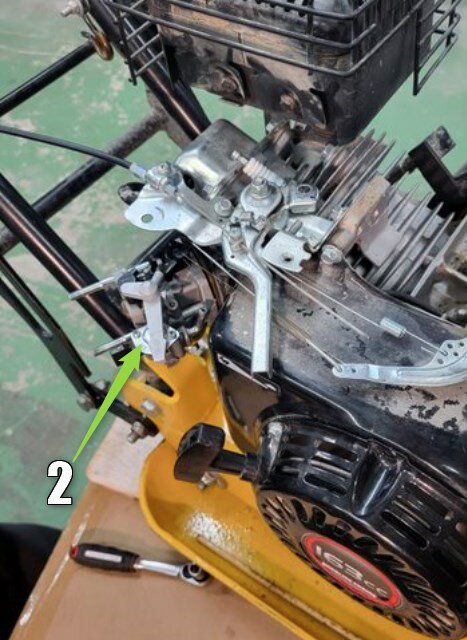 Rengjord och delvis demonterad förgasare på en motor med verktyg i bakgrunden.
