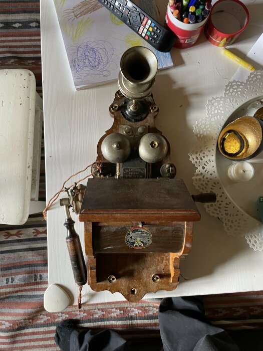 Gammal telefon från LM Ericsson på ett bord med rörtelefonlur och nummerskiva.