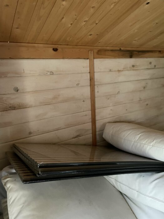 Trähörn i rum med säng och horisontella plankor, raglar syns skruvade på plankor.