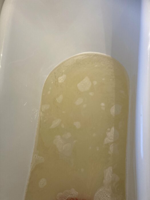 Gulbrunt vatten i ett badkar vilket antyder problem med järnrikedom i vattnet.