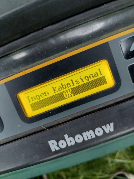 Digital display på en Robomow gräsklippare visar felmeddelandet "Ingen kabelsignal".