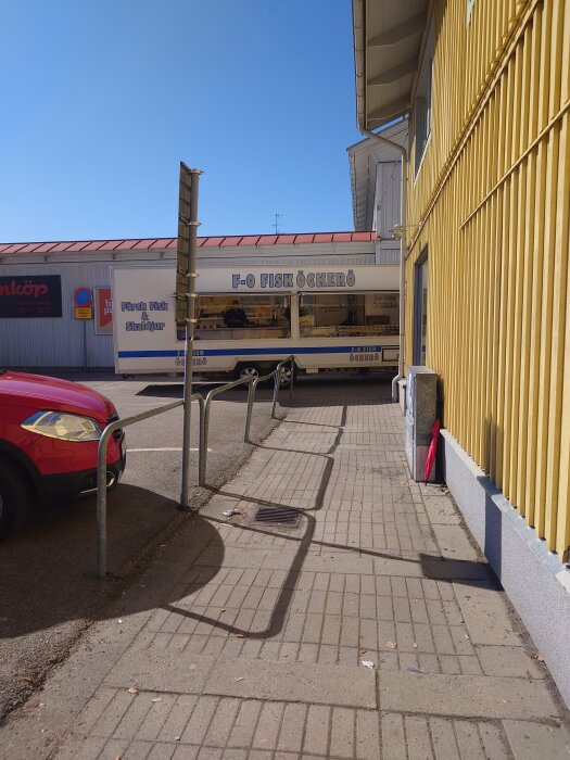Mobil fiskaffär parkerad vid en gul byggnad med texten "F.O FISK ÖCKERÖ" under en solig himmel.