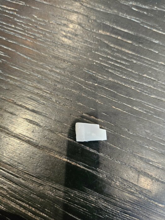 Vit spröjsclip på ett mörkt träbord.