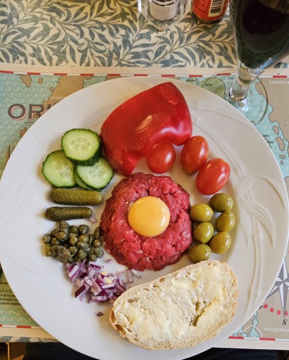 Råbiff med äggula, hackad lök, kapris, tomater, gurka och surdegsbröd på tallrik med Tempranillo vin.