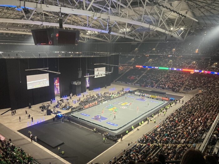 Inomhusevenemang i en stor arena med en idrottstävling och publik på läktarna.