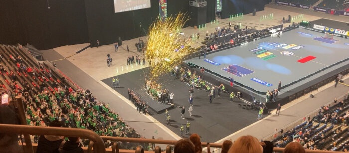 Publik i en arena ser på en idrottsevent med fyrverkerier och sportplaner.